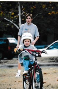 Child learning to ride bike with adult.