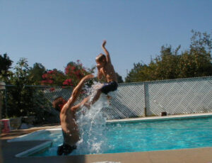 Child being thrown in swimming pool.