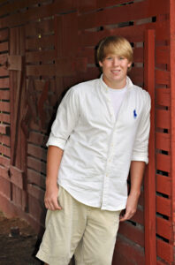 Young man leaning against a red wall.