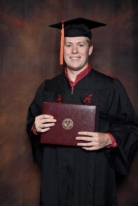 Graduate in cap and gown holding diploma.
