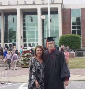 Graduate and woman posing outside a building.